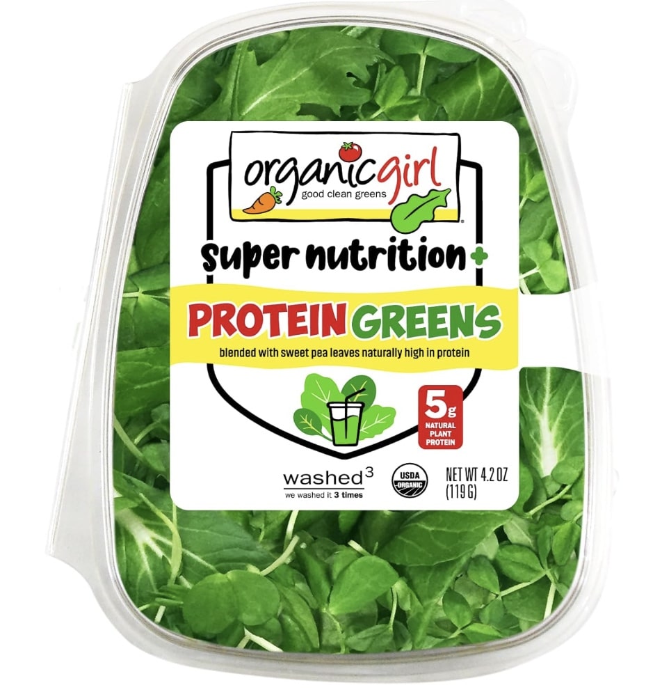 A clear plastic container of Organic Girl Super Nutrition Protein Greens mix, featuring bright green leaves inside and a colorful label highlighting "5g plant protein" and "blended with sweet pea leaves." One of my favorite side dishes. Net weight is 4.2 oz.